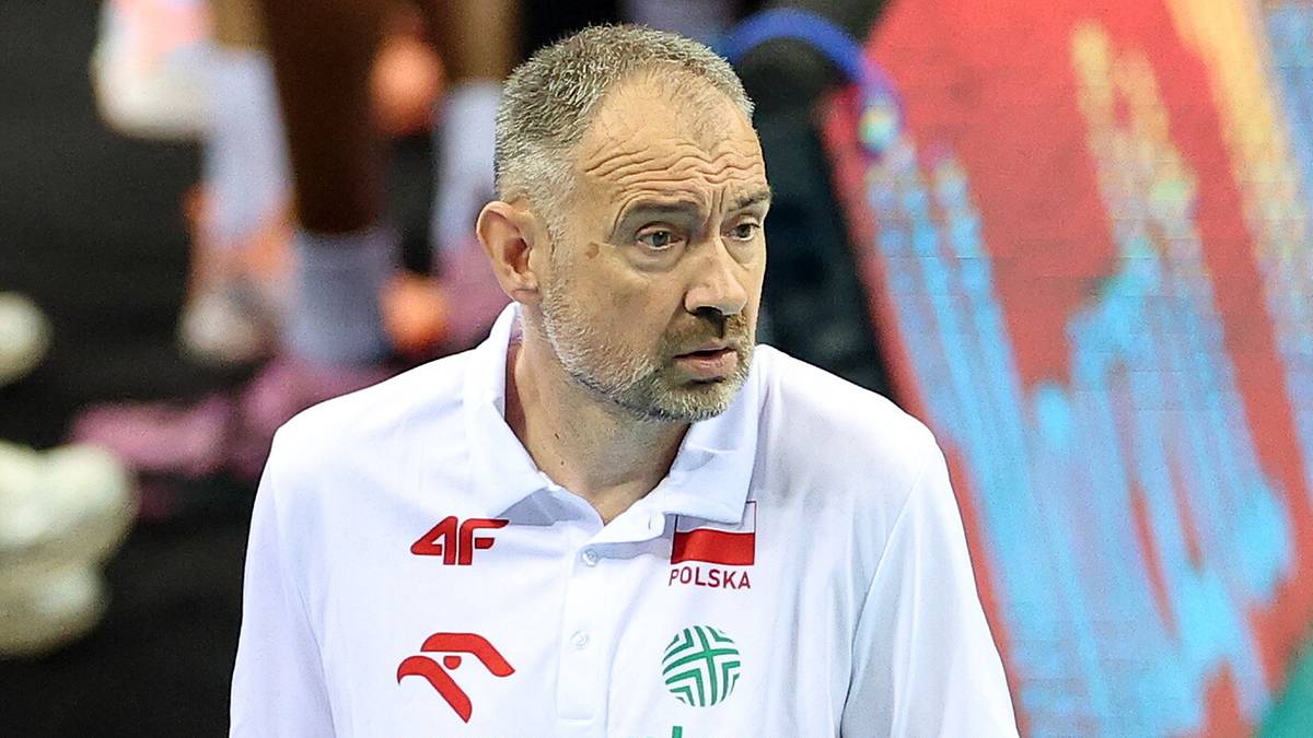 Portret mężczyzny w białej koszulce polo z widocznym logo "4F" i flagą Polski. Mężczyzna ma kr&oacute;tkie, siwe włosy i zarost, a jego spojrzenie jest skierowane w bok z wyrazem koncentracji.