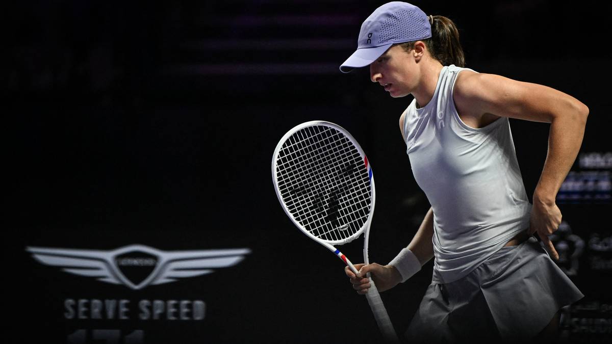 Tenisistka w białej koszulce i szarej spódniczce, trzymająca rakietę i patrząca w bok