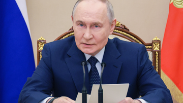 Władimir Putin, prezydent Rosji, siedzi przy stole i przemawia.