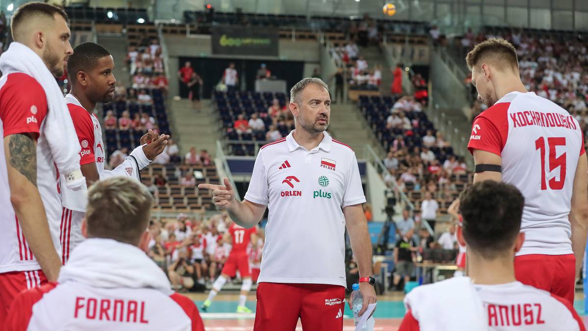 Siatkarze reprezentacji Polski w strojach biało-czerwonych, otoczeni przez trenera, dyskutują podczas meczu.