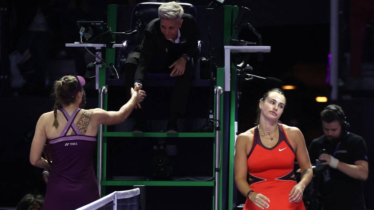 Dwie tenisistki, Aryna Sabalenka i Jelena Rybakina, podają sobie ręce po zakończonym meczu, z sędzią na podwyższeniu w tle.