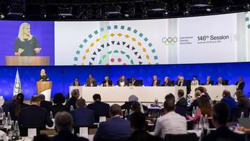 Sala konferencyjna podczas 146. Sesji Międzynarodowego Komitetu Olimpijskiego z ekranem wyświetlającym logo i datę wydarzenia.