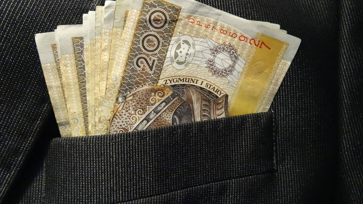 Zbliżenie na kieszeń marynarki z włożonymi do niej banknotami dwustuzłotowymi.