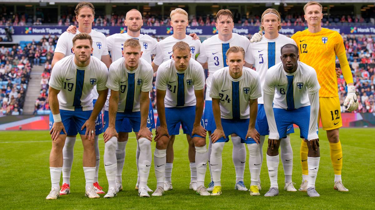 Drużyna piłkarska Finlandii w białych strojach pozuje do zdjęcia na boisku.
