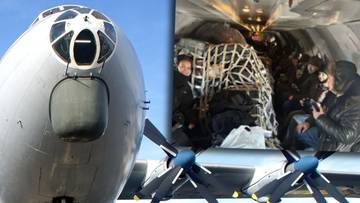 Fragment samolotu transportowego z widocznym ładunkiem i pasażerami siedzącymi obok bagaży.