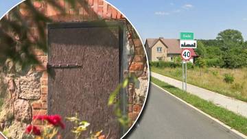 Zardzewiałe drzwi do kom&oacute;rki i droga z tablicą miejscowości Gaiki