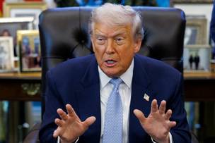 Donald Trump siedzi w fotelu i mówi, gestykulując rękami.