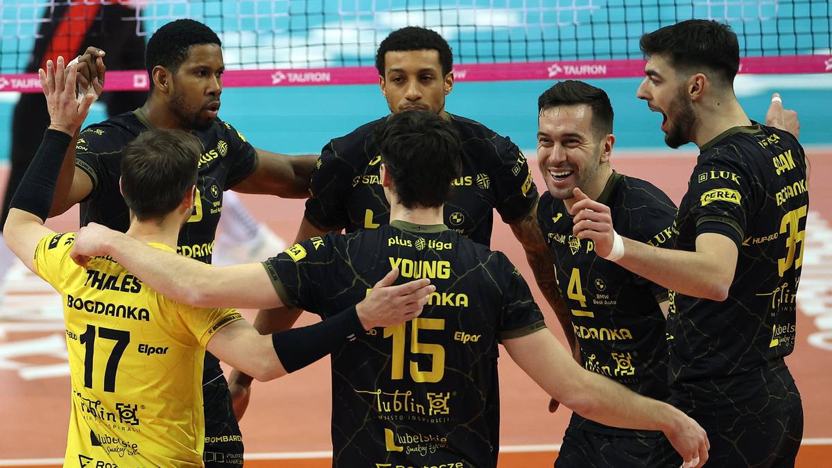 Grupa siatkarzy w strojach sportowych świętuje zwycięstwo na boisku.