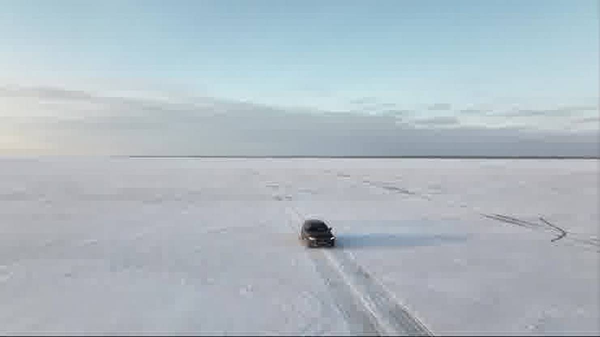 Samoch&oacute;d jedzie po zamarzniętej powierzchni z widocznymi śladami opon.