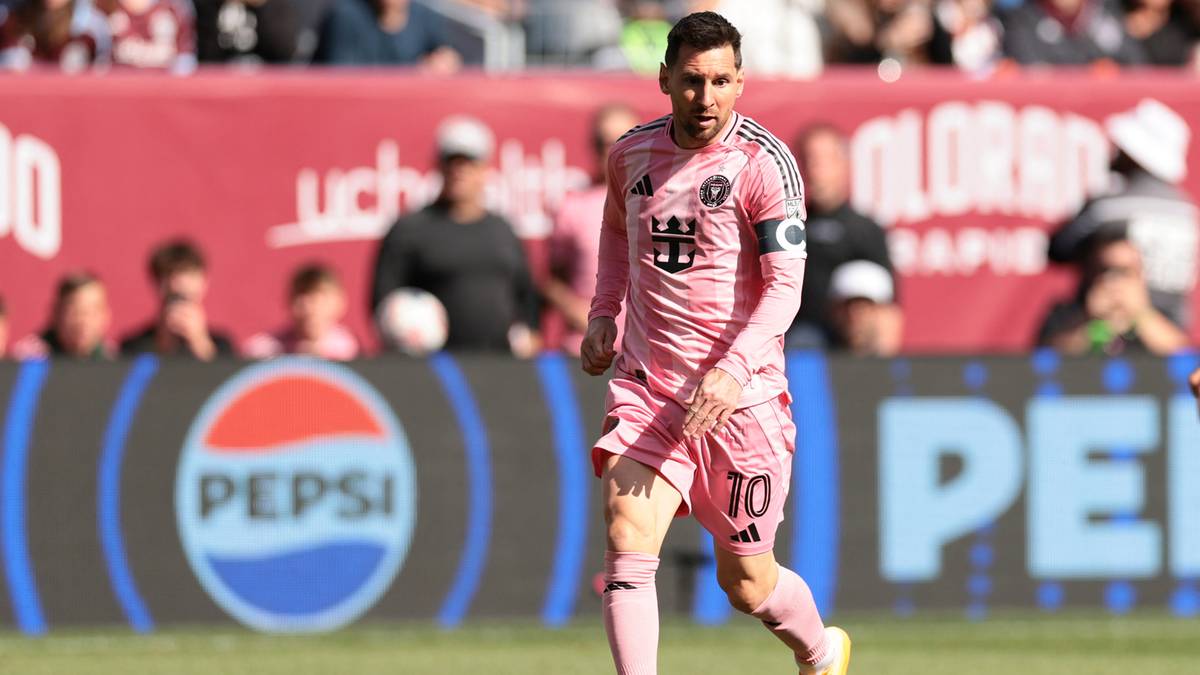 Piłkarz w r&oacute;żowym stroju z numerem 10 na plecach prowadzi piłkę na boisku.