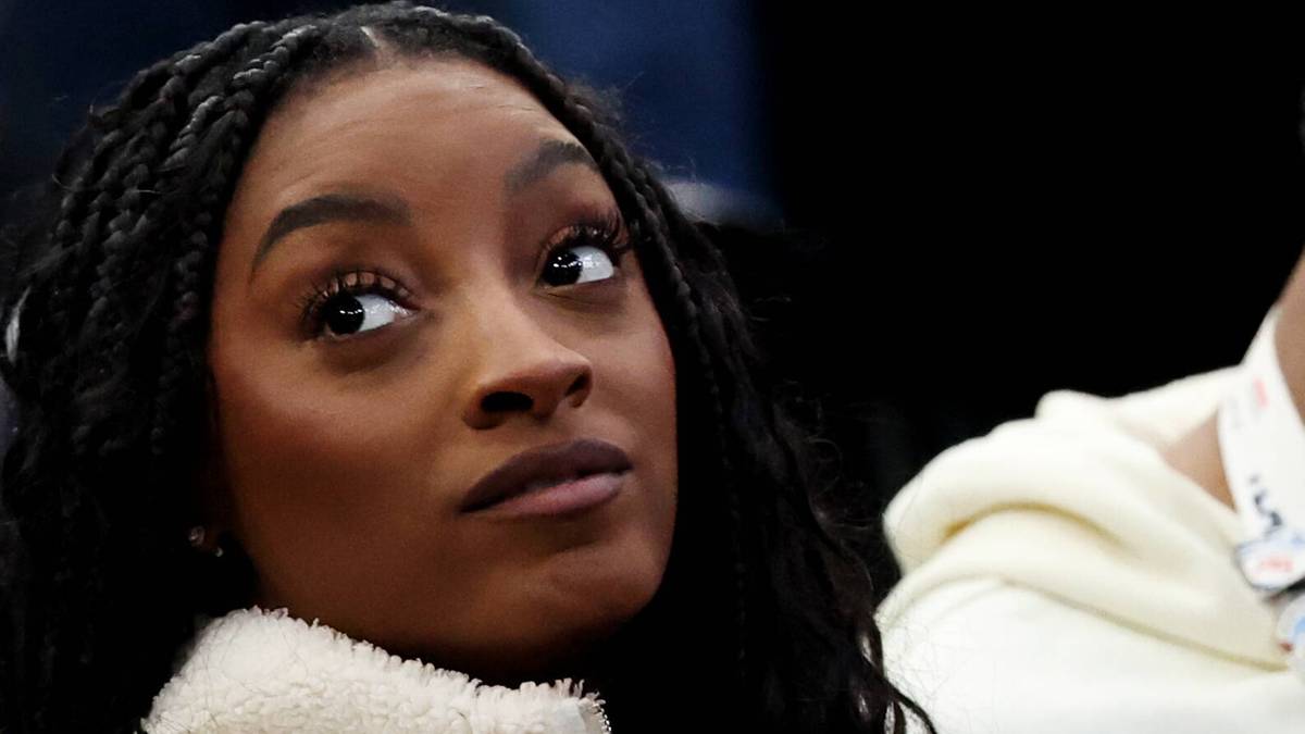 Zbliżenie na twarz Simone Biles z ciemnymi warkoczami, patrzącej w bok.