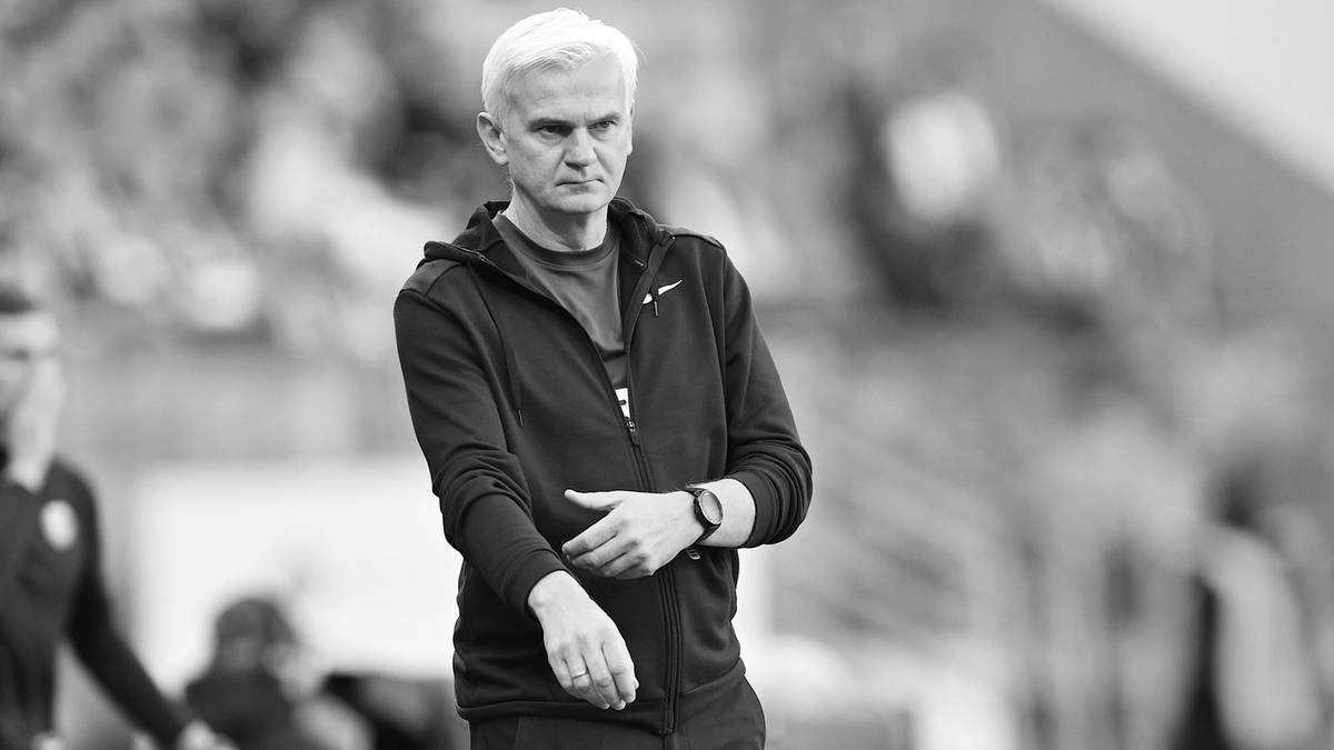 Mężczyzna w sportowym ubraniu stojący na tle stadionu.