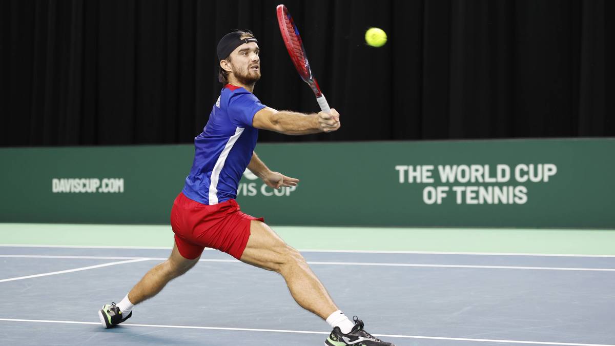 Tenisista w akcji, wykonujący forhend na korcie tenisowym.