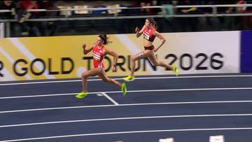 Dwie lekkoatletki w strojach sportowych biegną po bieżni, rywalizując w zawodach.
