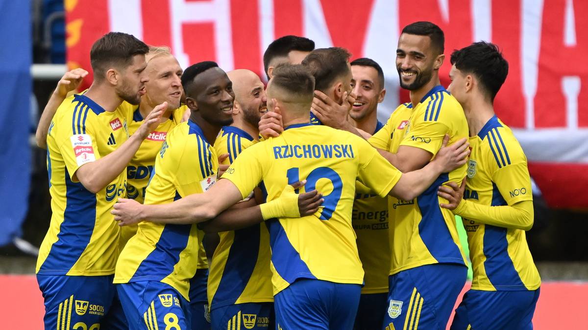 Grupa piłkarzy w żółto-niebieskich strojach świętuje razem, ściskając się i obejmując. Na koszulkach widoczne numery i nazwiska.