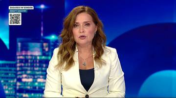 Kobieta w białej marynarce m&oacute;wi, na ekranie w tle widać nocny widok miasta.