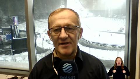 Michał Białoński w okularach i czarnej koszuli, z mikrofonem przed twarzą.