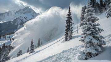 Lawina śnieżna schodząca po g&oacute;rskim zboczu wśr&oacute;d drzew, z g&oacute;rami w tle.