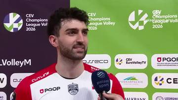 Mężczyzna z kr&oacute;tką, ciemną brodą i włosami, ubrany w biało-czerwony str&oacute;j sportowy, odpowiada na pytanie dziennikarza, trzymając mikrofon przed ustami. W tle widoczne są logo CEV Champions League Volley 2026 i nazwy sponsor&oacute;w.