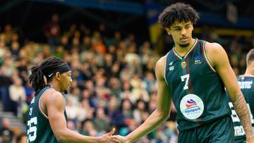 Dw&oacute;ch koszykarzy podaje sobie ręce na boisku.