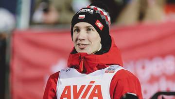 Mężczyzna w czapce z daszkiem i kurtce narciarskiej, ubrany w białą kamizelkę z czerwonym logo.