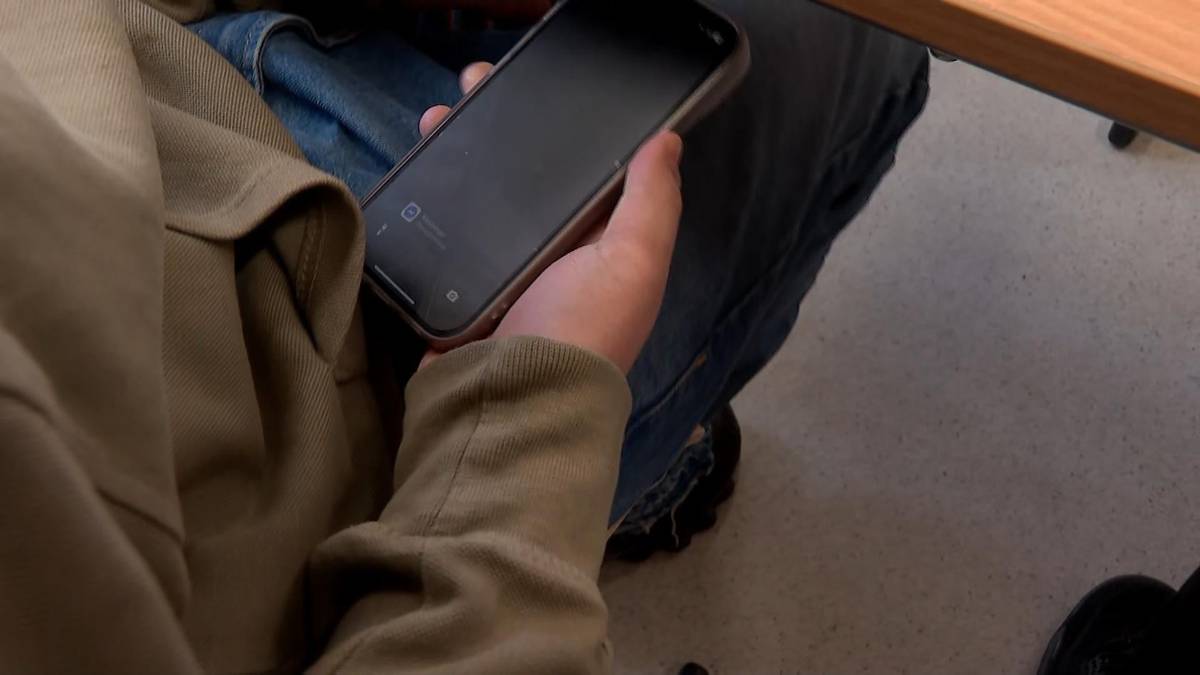 Osoba trzymająca smartfon w dłoni.