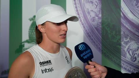 Iga Świątek w białej czapce z daszkiem i białej koszulce sportowej udziela wywiadu, trzymając w dłoni mikrofon Polsat Sport.