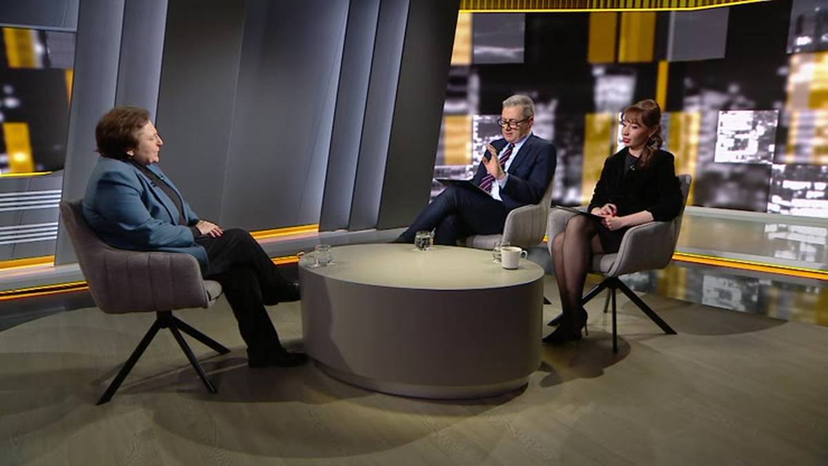 Trzy osoby siedzą w studiu telewizyjnym wok&oacute;ł okrągłego stołu. Po lewej siedzi kobieta w niebieskiej marynarce, zwr&oacute;cona twarzą do dw&oacute;ch pozostałych os&oacute;b. Pośrodku siedzi mężczyzna w garniturze i okularach, m&oacute;wiący z uniesioną dłonią. Po prawej siedzi kobieta w czarnej bluzce, słuchająca rozmowy.