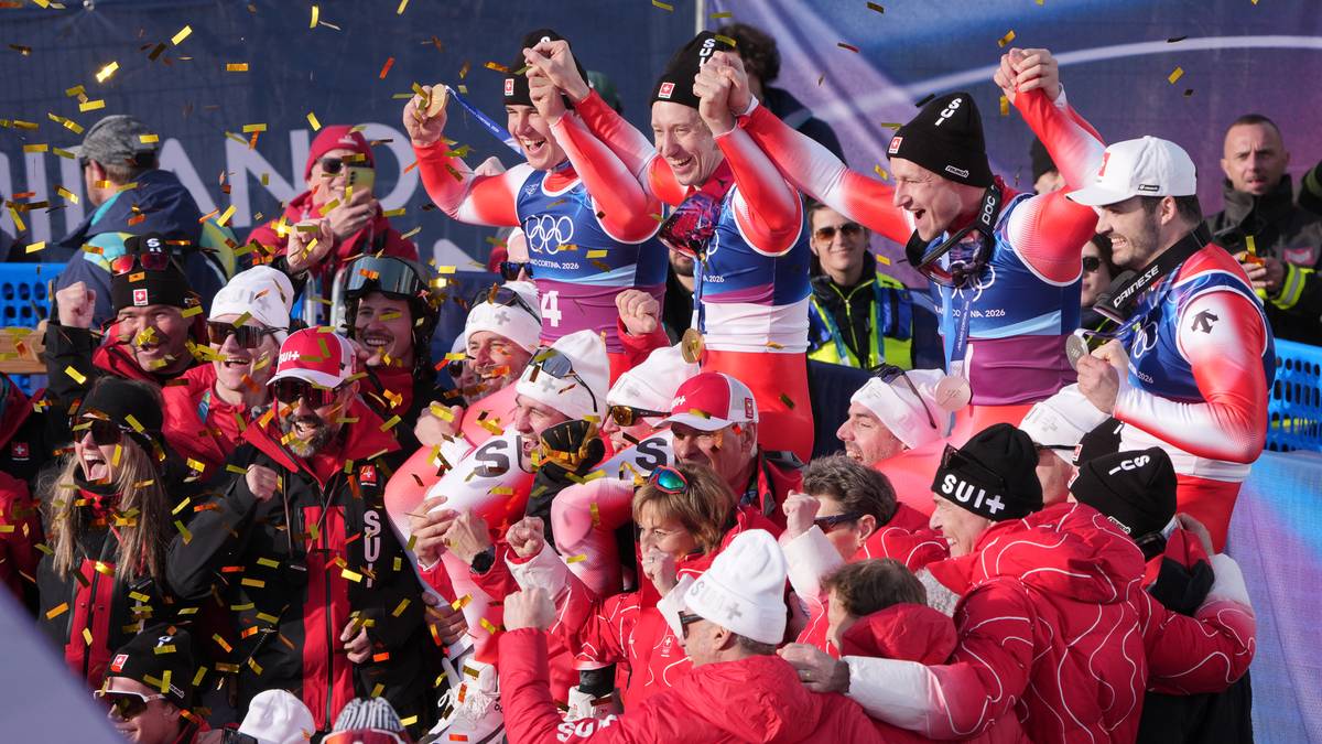 Grupa narciarzy w czerwono-białych strojach świętuje zwycięstwo, sypią się konfetti.