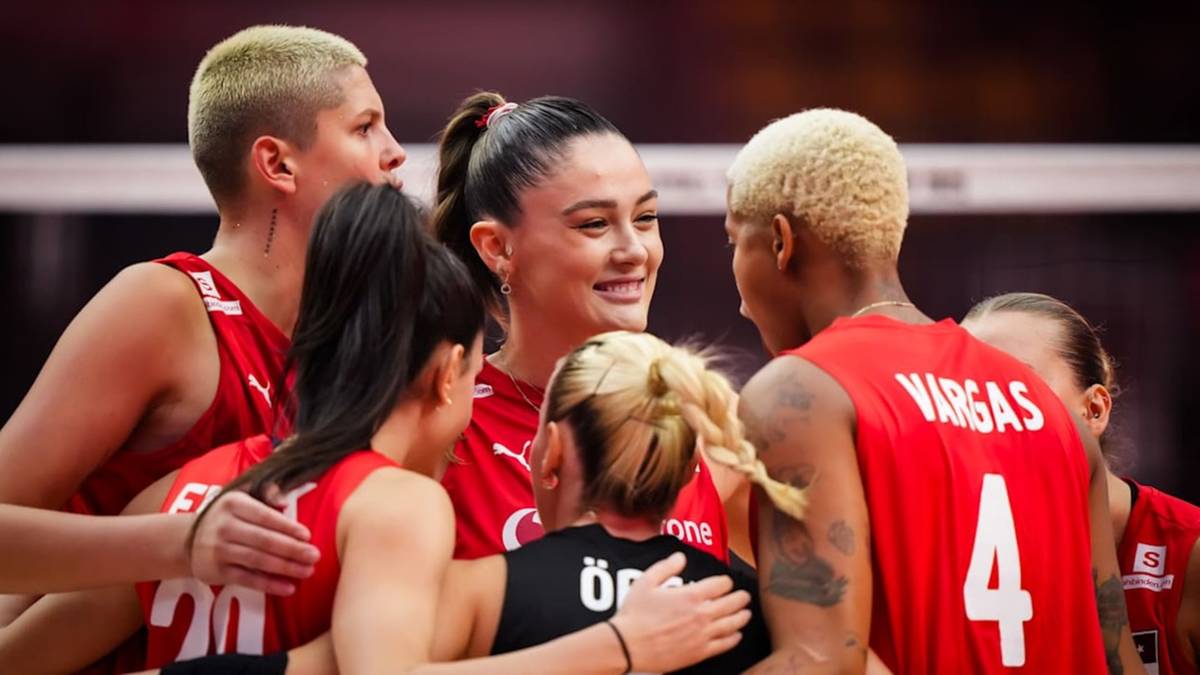 Grupa sportsmen, w tym zawodniczka z numerem 4 na plecach, otoczona przez koleżanki z drużyny, z uśmiechem na twarzy.