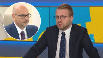 Mężczyzna w garniturze i okularach wypowiada się w studiu telewizyjnym, w tle widać okrągłą wstawkę z wizerunkiem innego mężczyzny.