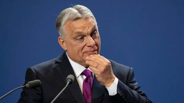 Viktor Orban, węgierski premier, w garniturze i krawacie, z ręką na podbr&oacute;dku.