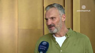 Tomasz Jankowski, mężczyzna z siwiejącą brodą i szarymi włosami, ubrany w zieloną koszulę, udziela wywiadu, trzymając mikrofon Polsat Sport.