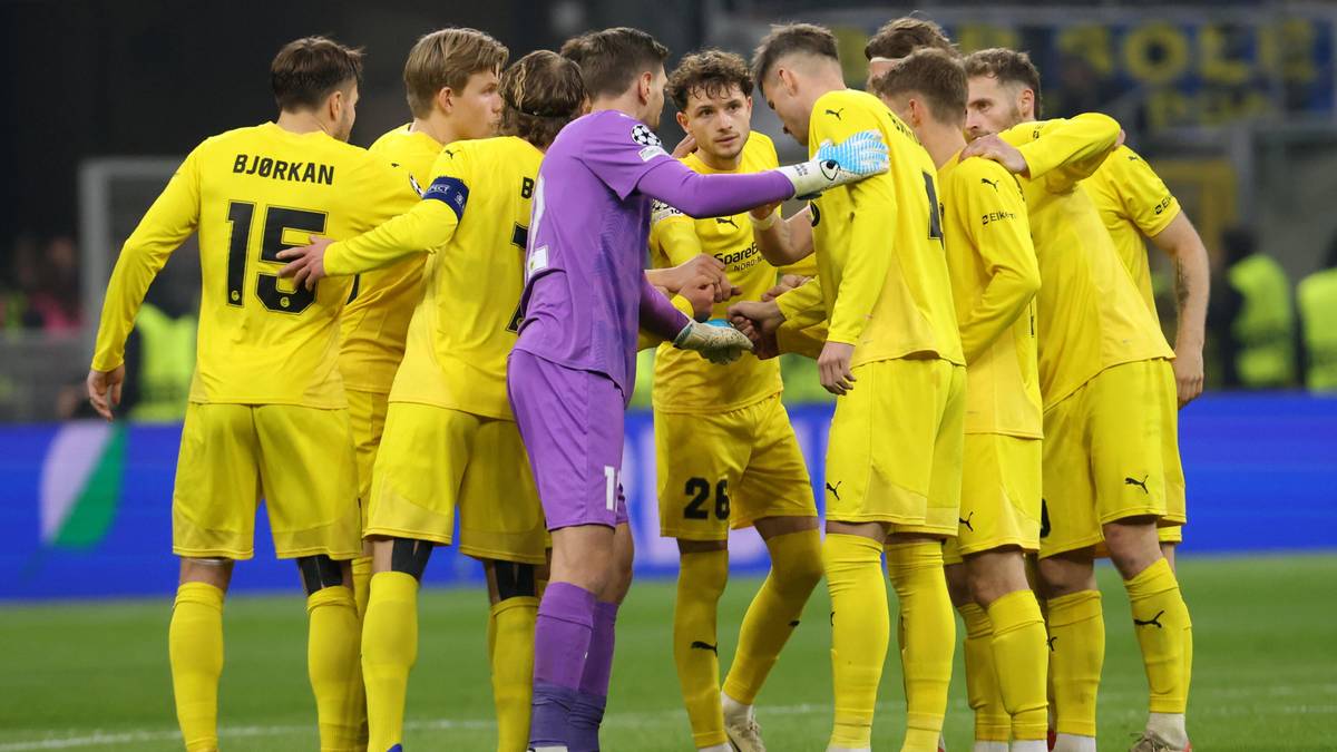 Drużyna piłkarska w ż&oacute;łtych strojach gromadzi się w okręgu na boisku, świętując zwycięstwo.