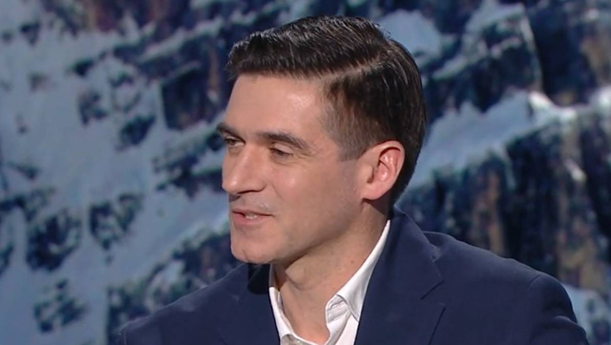 Portret mężczyzny w garniturze na tle zaśnieżonych g&oacute;r.