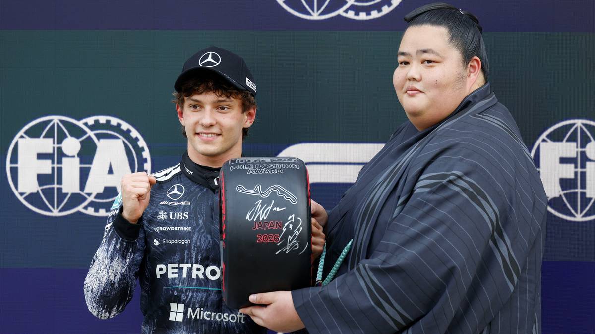 Kierowca Formuły 1 Antonelli odbiera trofeum na podium w towarzystwie mężczyzny w stroju japońskim.