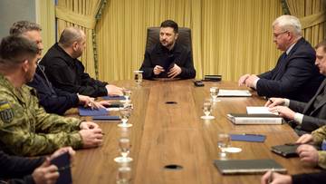 Wołodymyr Zełenski siedzi przy stole w otoczeniu współpracowników podczas spotkania.