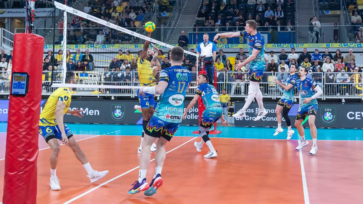 Siatkarze podczas meczu Ligi Mistrz&oacute;w, jeden z zawodnik&oacute;w skacze do ataku nad siatką.