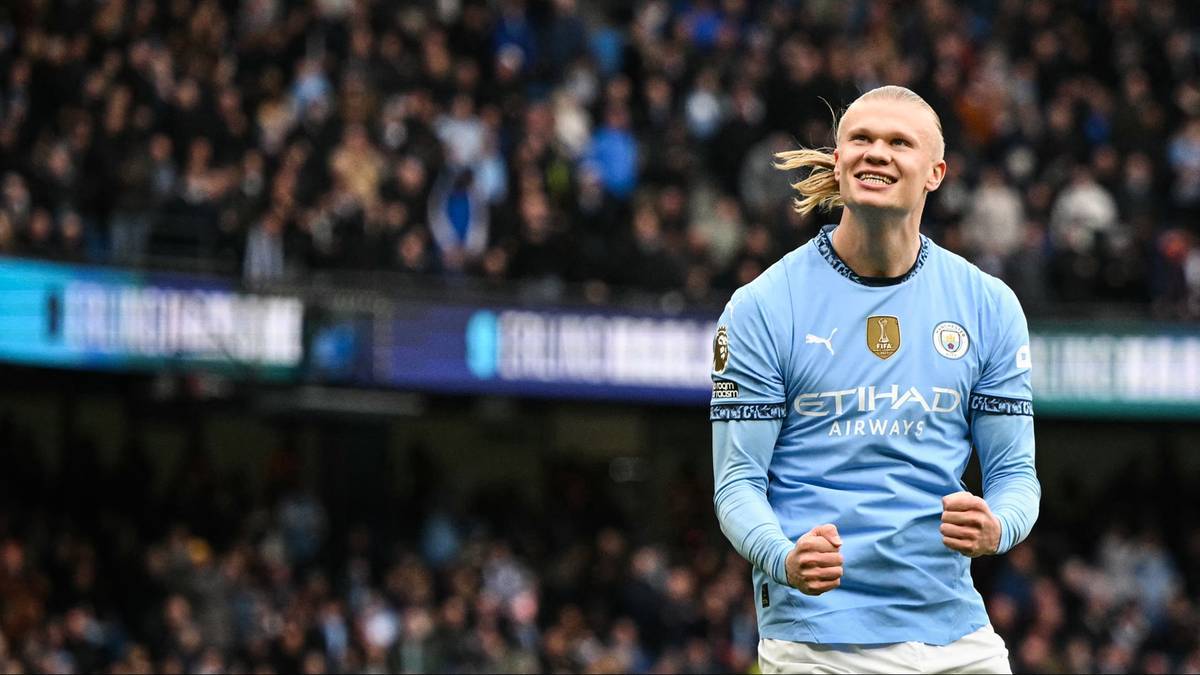 Piłkarz Erling Haaland w koszulce Manchesteru City świętuje z zaciśniętymi pięściami na tle trybun stadionu.
