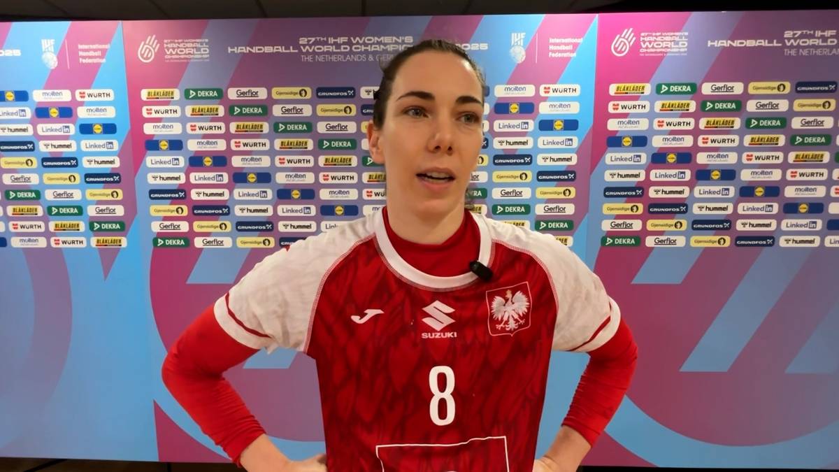 Monika Kobylińska, zawodniczka piłki ręcznej, w czerwonej koszulce z numerem 8 i godłem Polski, udziela wywiadu na tle ściany z logotypami.