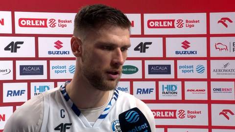 Portret koszykarza Michała Mielczarka na tle ścianki z logo sponsor&oacute;w.