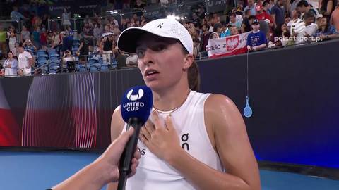 Iga Świątek w białej czapce z daszkiem i białej koszulce z ręką na sercu, podczas wywiadu.