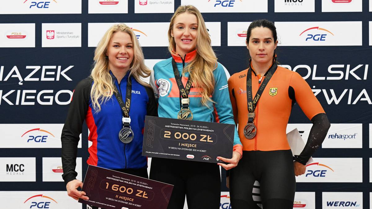 Trzy kobiety na podium, dwie z nich trzymają tabliczki z kwotami pieniężnymi, a wszystkie mają medale na szyjach.