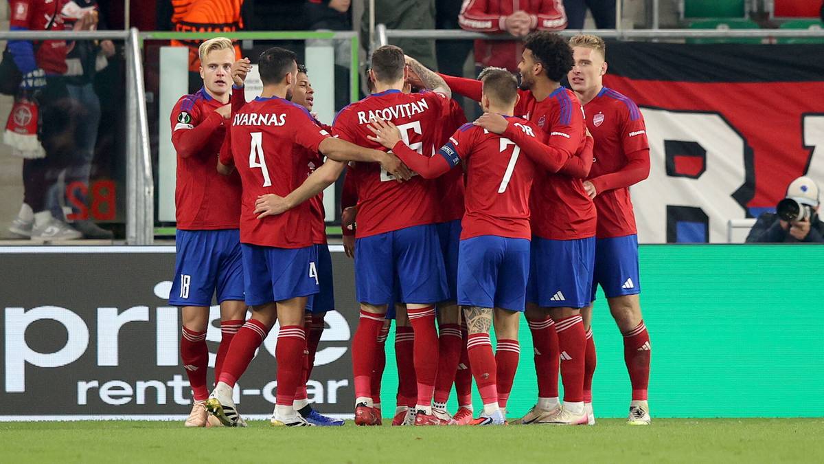 Drużyna piłkarska w czerwonych strojach świętuje po meczu.