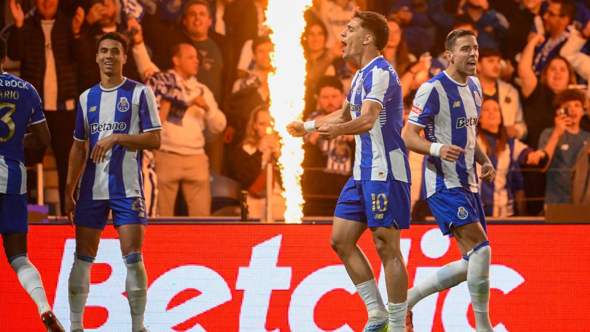 Piłkarze FC Porto w niebiesko-białych strojach świętują zdobycie bramki, na tle płomieni i kibic&oacute;w.