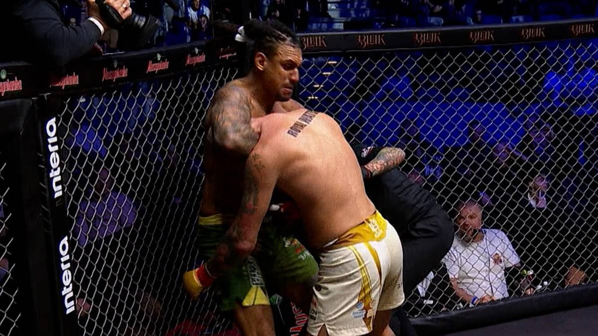 Dwóch zawodników MMA walczy w klatce, jeden próbuje duszenia gilotynowego.