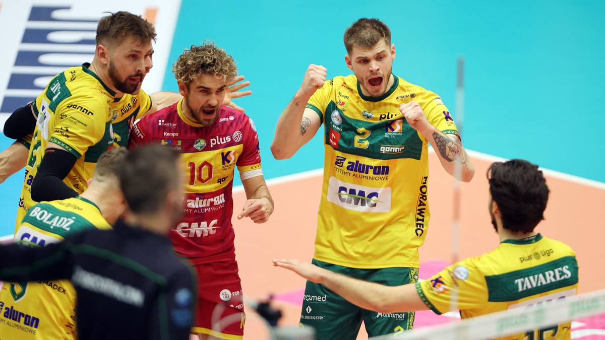 Siatkarze drużyny Aluron CMC Warta Zawiercie świętują podczas meczu, jeden z nich w czerwonej koszulce rozmawia z kolegą z drużyny.
