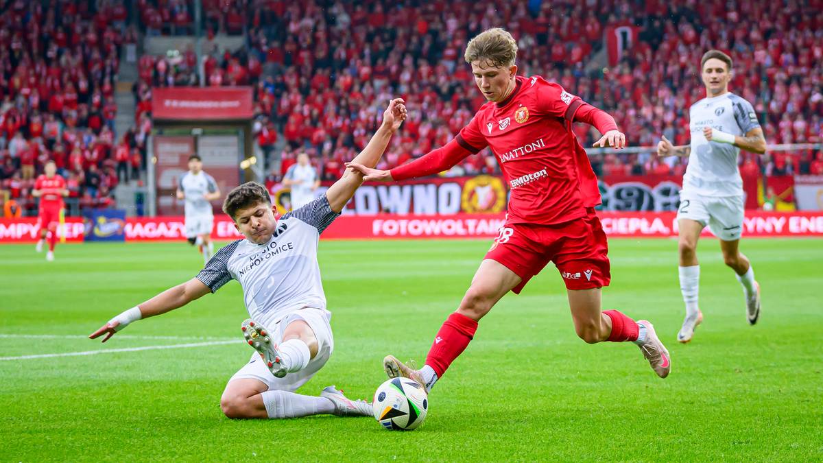 Dwóch piłkarzy walczących o piłkę na boisku podczas meczu.