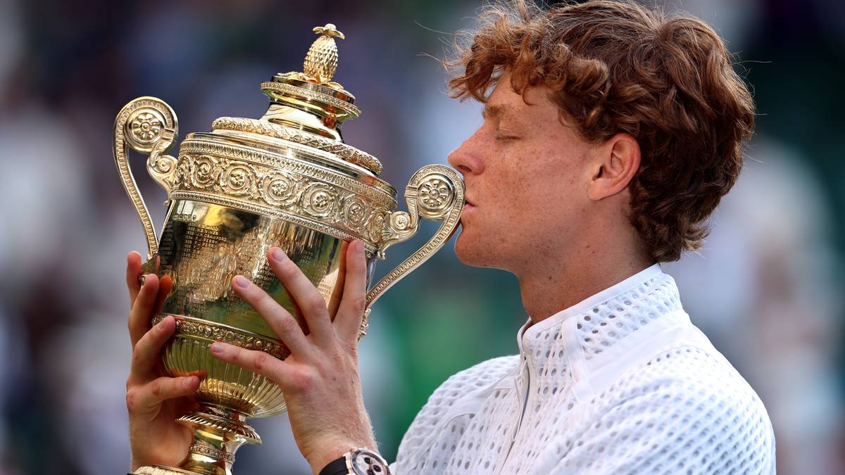 Jannik Sinner całuje złote trofeum Wimbledonu.