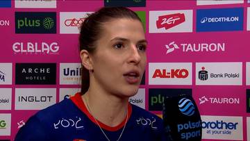 Portret kobiety z opaską na włosach, m&oacute;wiącej do mikrofonu. W tle widnieje ściana z logo sponsor&oacute;w.